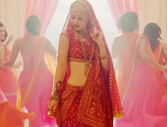 Popstar Iggy Azalea in einem rot-goldenen traditionellen nordindischen Hochzeitskleid, getragen in einem Musikvideo.